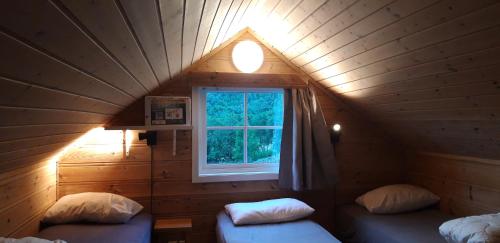 a small attic room with a window and two beds at Stalheim Fjord og Fjellhytter in Stalheim
