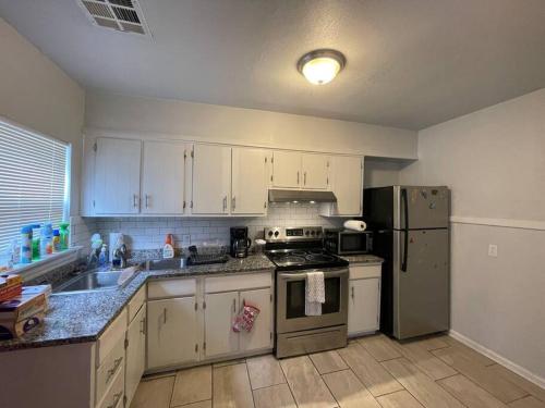 a kitchen with white cabinets and a stainless steel refrigerator at Quiet Comfort minutes from BOK and downtown Tulsa in Tulsa
