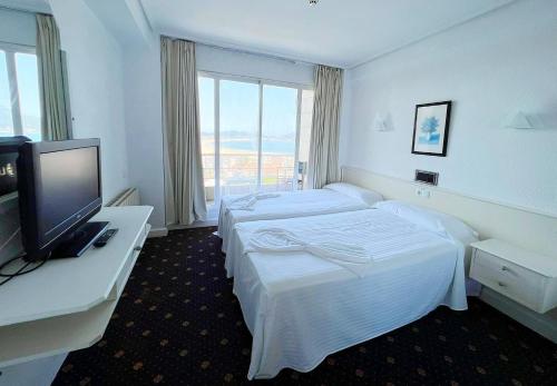 a hotel room with two beds and a flat screen tv at Hotel Miramar Laredo in Laredo
