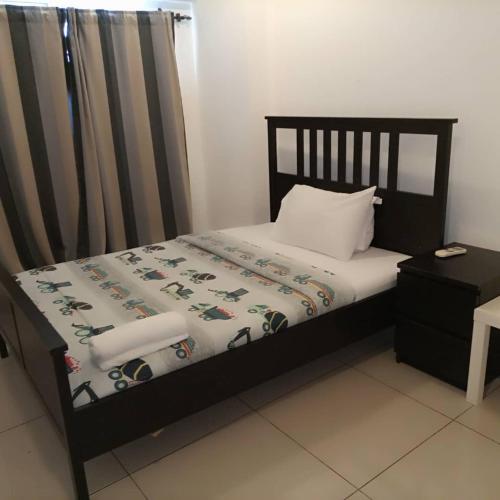 1 dormitorio con 1 cama con marco negro y sábanas blancas en Gallery by KMAX PROPERTY, en Accra
