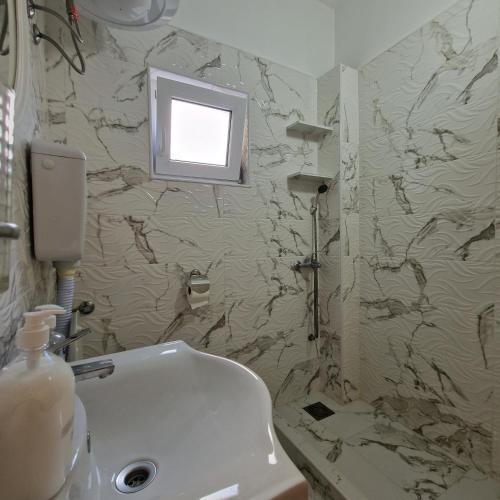 a bathroom with a sink and a television on the wall at Apartmani Vlahović in Sutomore