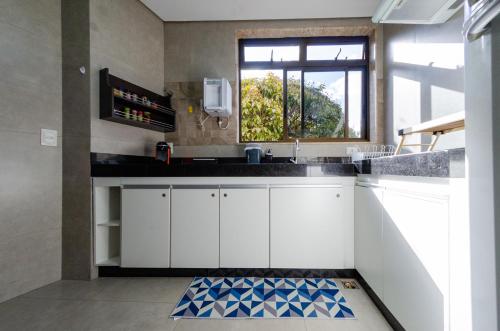 una cocina con armarios blancos y una ventana en apartamentos Coração Eucarístico en Belo Horizonte