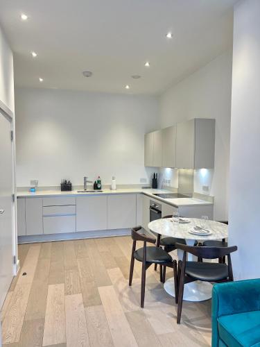 Luxury Modern 1 Bed Apartment في لندن: مطبخ مع طاولة وكراسي في غرفة