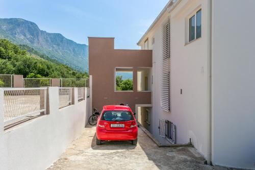 a red car parked in a parking lot next to a building at Studio Podaca 6736b in Podaca