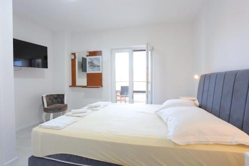 Schlafzimmer mit einem großen weißen Bett mit blauem Kopfteil in der Unterkunft Apartment Baska Voda 6773a in Baška Voda