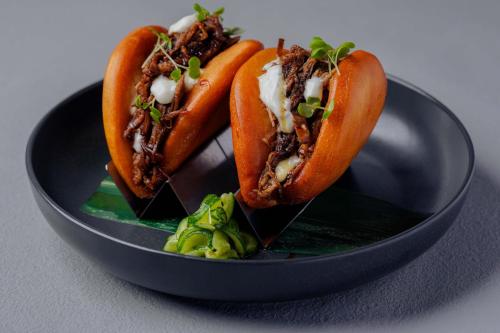 two chili dogs in a black bowl with a green salad at Le Meridien Abu Dhabi Resort in Abu Dhabi