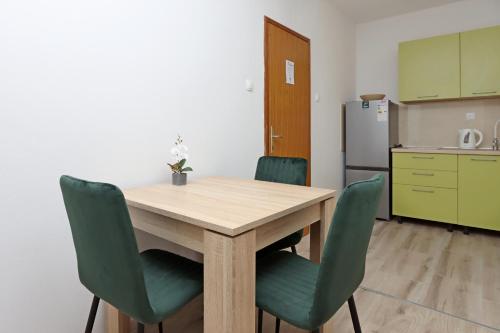 kuchnia z drewnianym stołem i zielonymi krzesłami w obiekcie Studio Mandre 3084b w mieście Kolan