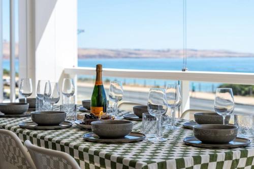 a table with a bottle of wine and glasses at Reef House: Pool • Beachfront • Near Wineries in Aldinga Beach