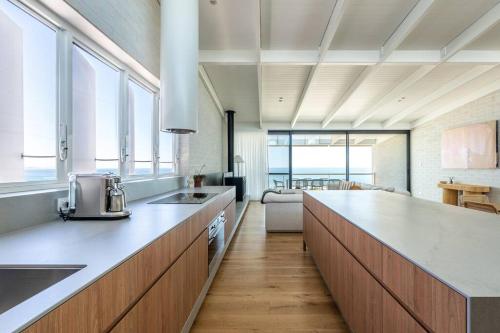 a large kitchen with a counter top and some windows at Reef House: Pool • Beachfront • Near Wineries in Aldinga Beach