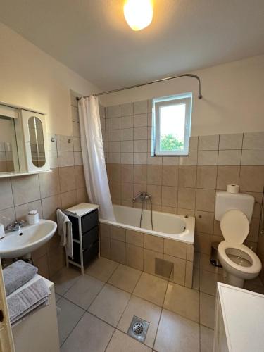 a bathroom with a tub and a toilet and a sink at Relax and Unwind: Family-Friendly House near Zadar in Zagrad in Zadar