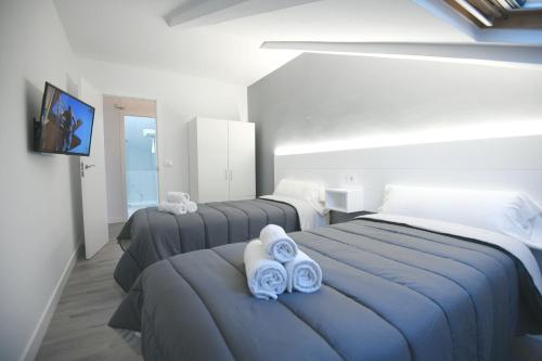 ein Schlafzimmer mit 3 Betten und blauen Handtüchern darauf in der Unterkunft Apartamentos Naturmar in Raxo