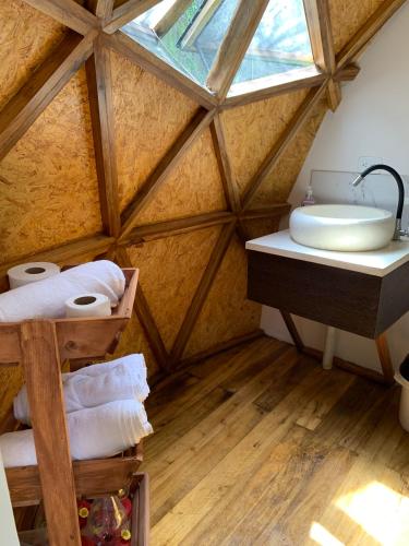 un bagno mansardato con lavandino e finestra di Magic Elf Glamping a Mindo