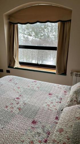 a bedroom with a window and a bed with a flowered blanket at DEPARTAMENTOS TERMAS DE CHILLAN in Nevados de Chillan
