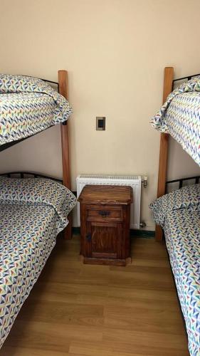 a room with two beds and a night stand between them at DEPARTAMENTOS TERMAS DE CHILLAN in Nevados de Chillan