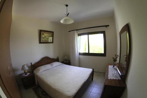a bedroom with a bed and a window and a mirror at Eve Pissouri Rozaki Villa in Pissouri