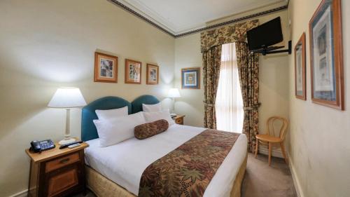 a hotel room with a bed and a television at Royal Exchange Hotel in Broken Hill