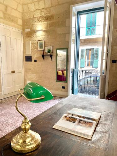 a table with a green lamp and a book on it at Vohis Luxury House - Fast Wi-fi & Easy parking in Lecce