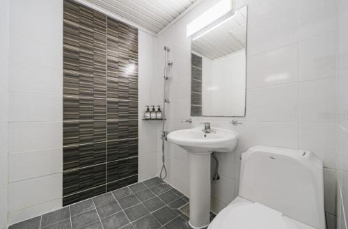 a white bathroom with a toilet and a sink at The Oakra Hotel in Jeju