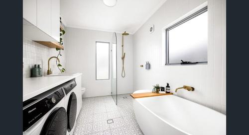 bagno bianco con vasca e lavatrice. di The South bay's home-Big RoomA a Sydney