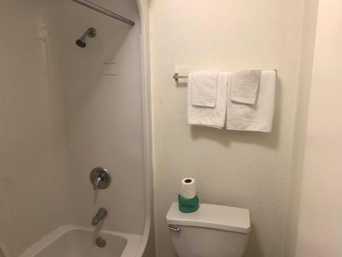 a bathroom with a toilet and a shower and towels at Deluxe Inn Austin in Austin