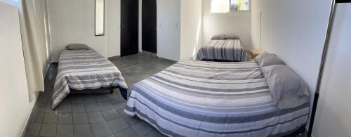 2 Einzelbetten in einem Zimmer mit Fliesenboden in der Unterkunft Casa Carlota Mazatlán in Mazatlán