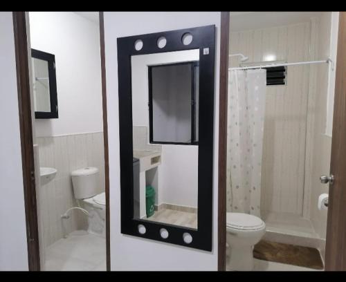 y baño con espejo, aseo y ducha. en Acogedor apartamento en la ciudad de las araucarias en Santa Rosa de Cabal