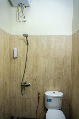a bathroom with a toilet with a shower head at GRAND KHALIFAH Guesthouse in Sumbawa Besar