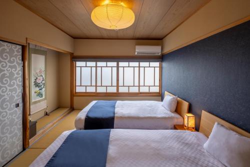 a room with two beds and a window at Machiya Oozora in Kyoto