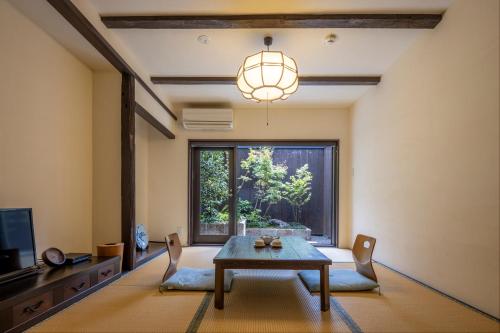 a living room with a table and chairs and a window at Machiya Oozora in Kyoto