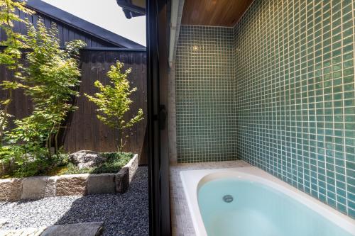 Machiya Oozora في كيوتو: حوض استحمام في حمام به بلاط أخضر