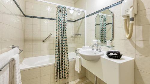 a bathroom with a sink and a tub and a toilet and a mirror at Royal Exchange Hotel in Broken Hill