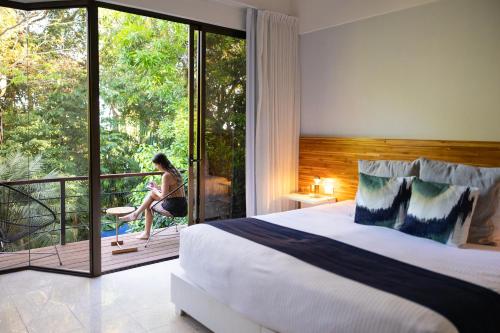 a woman is sitting on the balcony of a bedroom at Hotel Nya in Montezuma