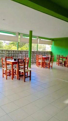 um restaurante com mesas e cadeiras de madeira e paredes verdes em Hotel posada onix xilitla em Xilitla