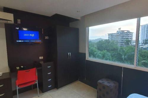 um quarto com uma grande janela e uma cadeira vermelha em R.1108 Lindo aparta estudio equipado tipo ejecutivo. na Cidade do Panamá