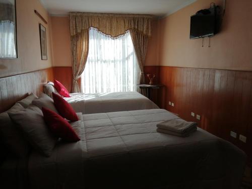 a bedroom with two beds in front of a window at Huaytusive Inn Hotel in Puno