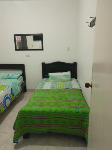 a bedroom with a bed with a green comforter at HOTEL CASA BLANCA in Popayan