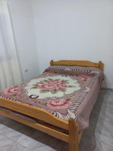 łóżko z kwiatowym kocem na górze w obiekcie Mahuida departamentos w mieście Malargüe