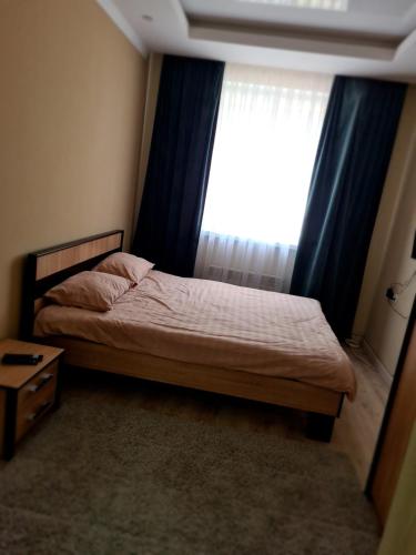 Schlafzimmer mit einem Bett und einem Fenster mit blauen Vorhängen in der Unterkunft New Аpartment Balti in Bălţi