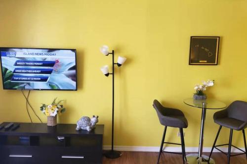a living room with a tv and a table and chairs at Waikiki condo -18F in Honolulu