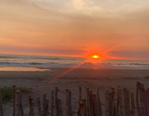 a sunset on the beach with a wooden fence at Tres Velas Surf in Celestino Gasca
