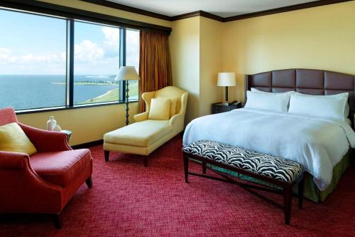 um quarto de hotel com uma cama e uma cadeira e uma janela em New Orleans Marriott Metairie At Lakeway em Metairie