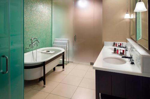 a bathroom with a tub and a sink and a shower at New Orleans Marriott Metairie At Lakeway in Metairie