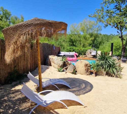 two chairs and an umbrella and a swimming pool at Complejo Oasis Beach sobre el Rio in Huerta