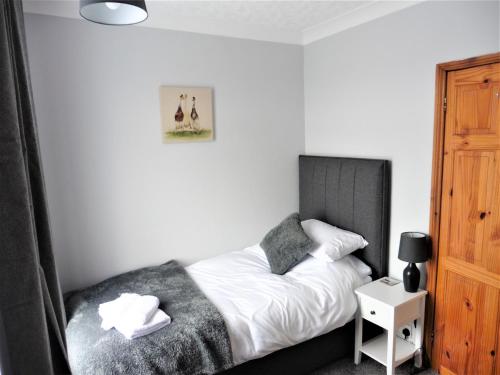 a bedroom with a bed with a black headboard at 3BD House Minutes from Great Yarmouth Seaside in Great Yarmouth