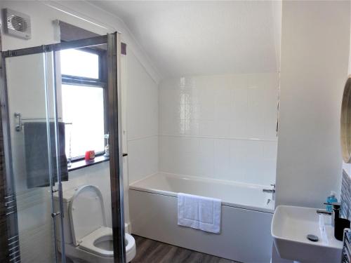 a bathroom with a tub and a toilet and a sink at 3BD House Minutes from Great Yarmouth Seaside in Great Yarmouth