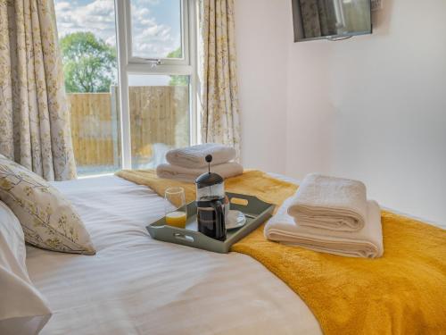un letto con vassoio, asciugamani e una bottiglia di profumo di West End Farm Lodge Alabaster a Lydbrook