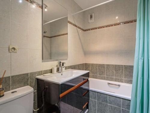 een badkamer met een wastafel, een toilet en een spiegel bij Appartement Hendaye, 2 pièces, 2 personnes - FR-1-2-436 in Hendaye