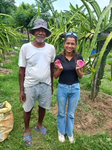 a man and a woman holding up pink fruit at Riverside Homes in Deorāli