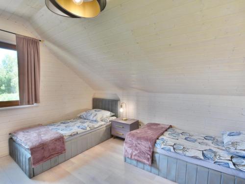 two twin beds in a room with a window at Comfortable holiday home, sauna hot tub included in Sulechowo