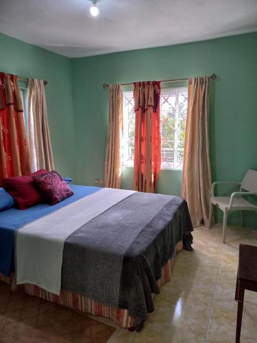1 dormitorio con 1 cama en una habitación con paredes verdes en Sevelle Meadows 2 Extended Stay en Spanish Town